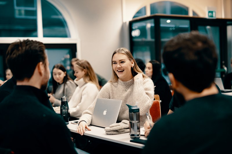 Studenter snakker sammen rundt et bord. Bachelor ledelse og servicestrategi.