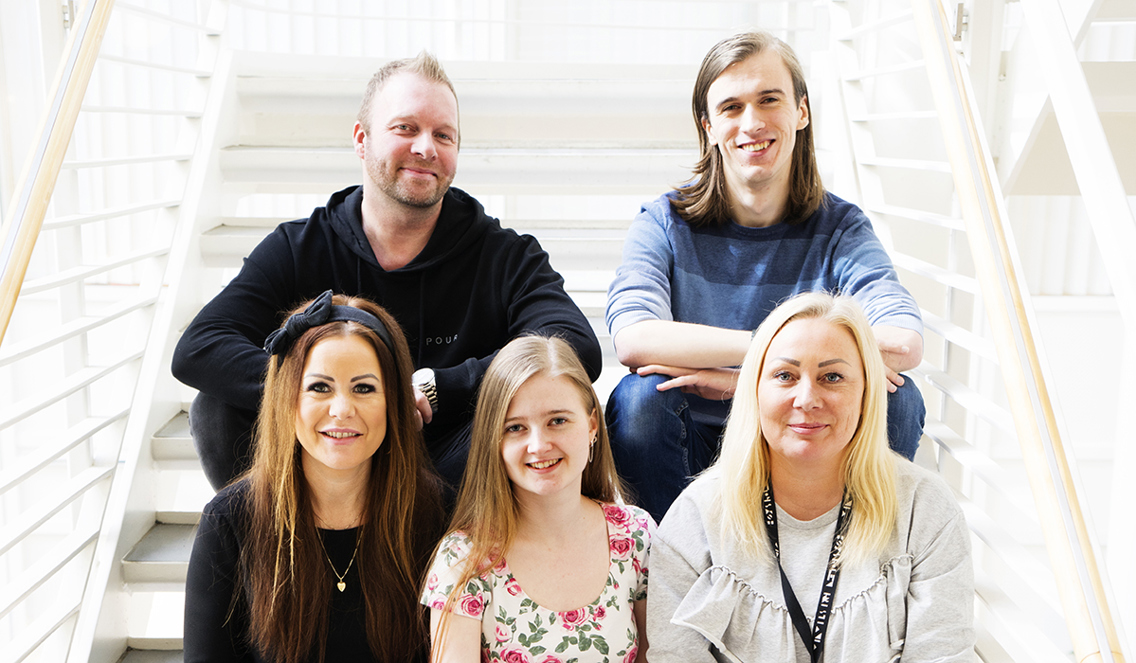 5 mennesker sitter i en trapp og smiler.