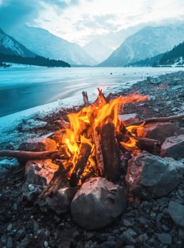 Et bål ved et vann på en grå og kald ettermiddag