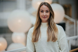 Ung kvinne med lyst hår i hvit genser.