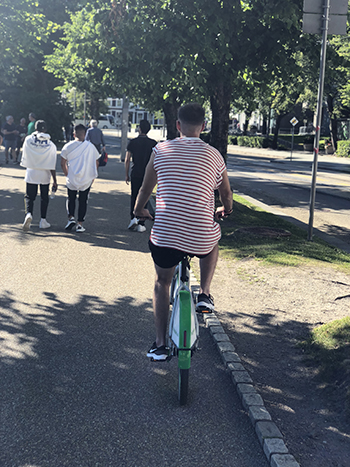 Foto av ung mann som sykler på en bysykkel.