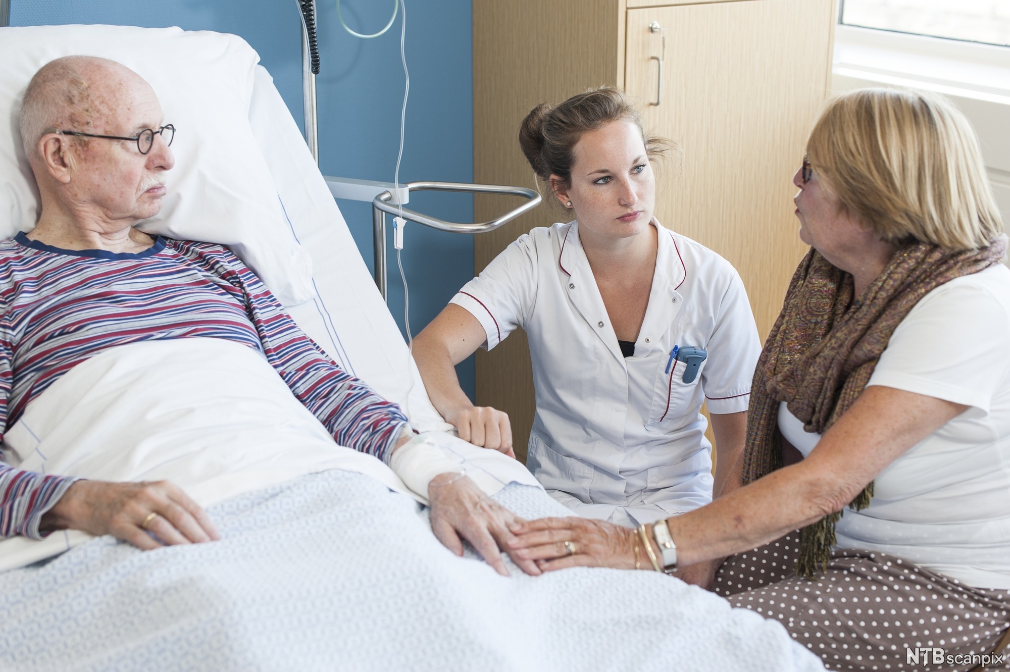 Sykepleier samtaler med pasient og pårørende.