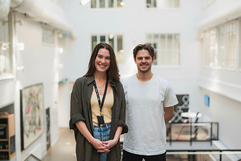 To studenter som står ved siden av hverandre og smiler til kamera.