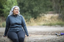 Woman in workout clothes sitting out in nature.