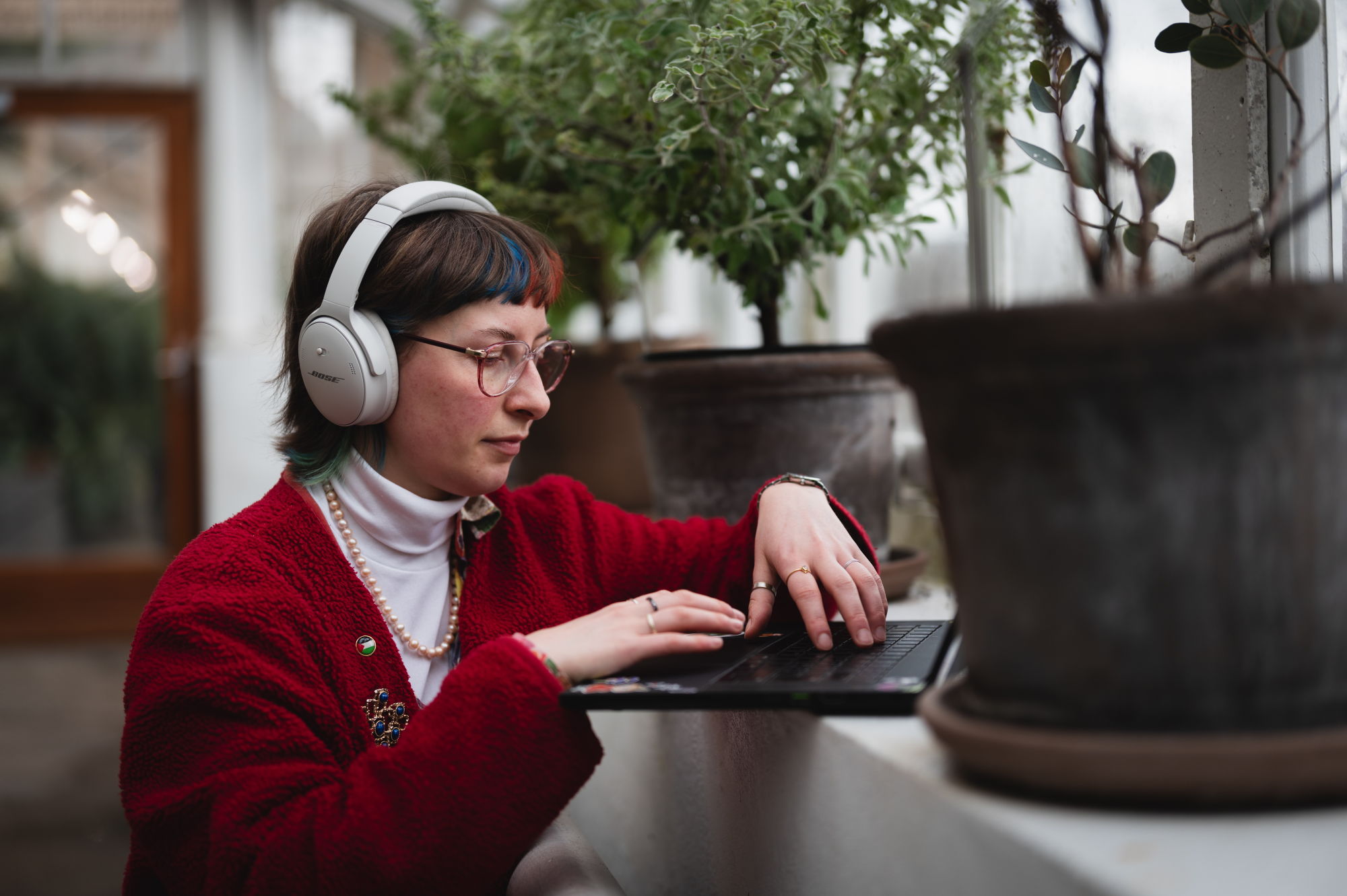 Oda jobber på en PC i et lyst kontorlandskap med mange planter.