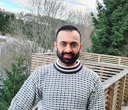 Foto av Juned som står i strikkegenser ute på en veranda.