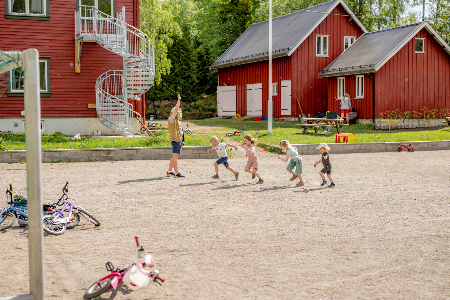 Barn leker utendørs på SFO mens en voksen passer på.