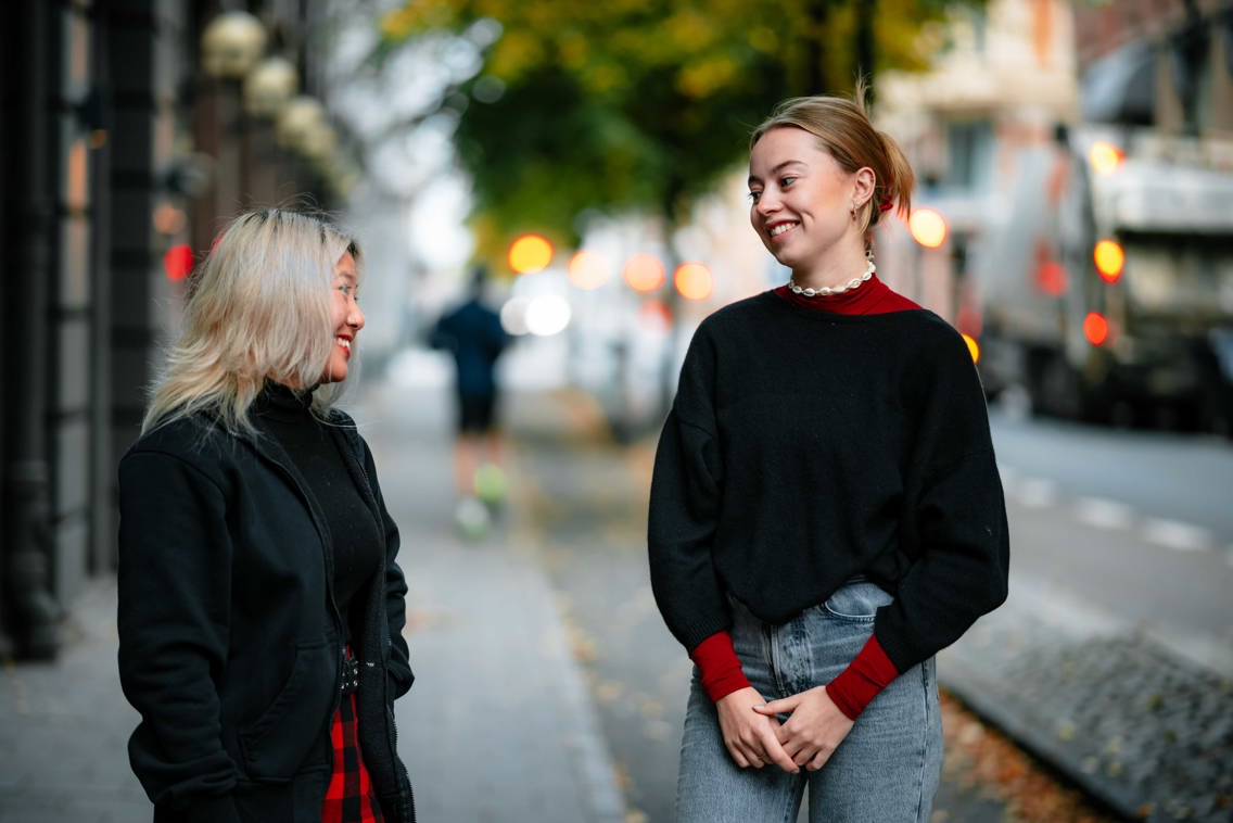 To jenter smiler mot hverandre på et fortau. 