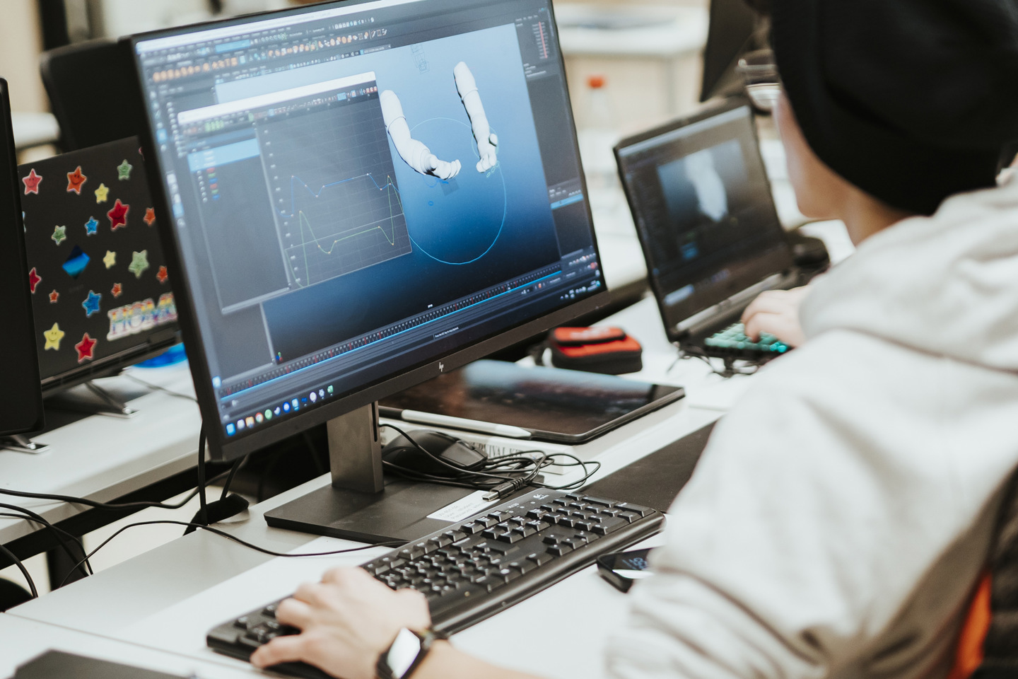 Student jobber med PC, hen programmerer hvordan armer og hender skal bevege seg på skjerm.