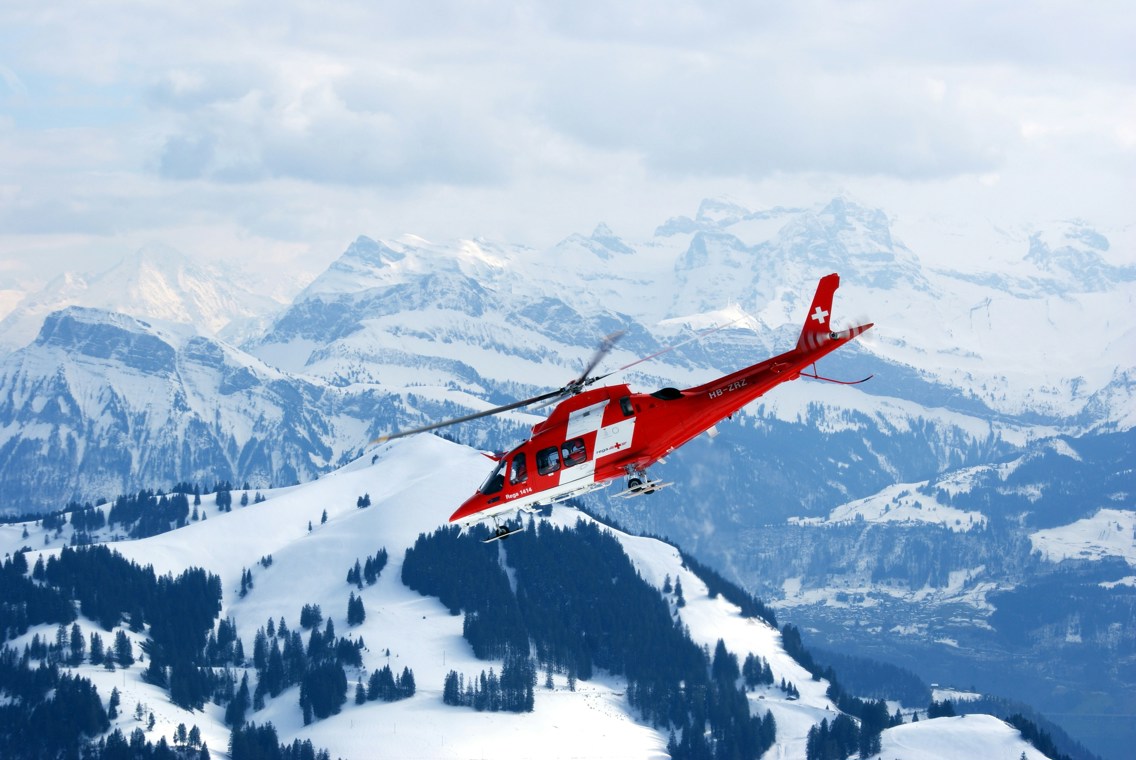 Helikopter flyr over snødekte fjell