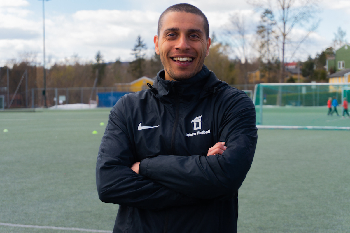 Muslim står på en fotballbane med et stort smil