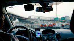 En mann kjører bil på motorveien med google gps som viser vei 