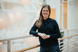 Foto av kvinne i sort skjorte som lener seg på et rekkverk.