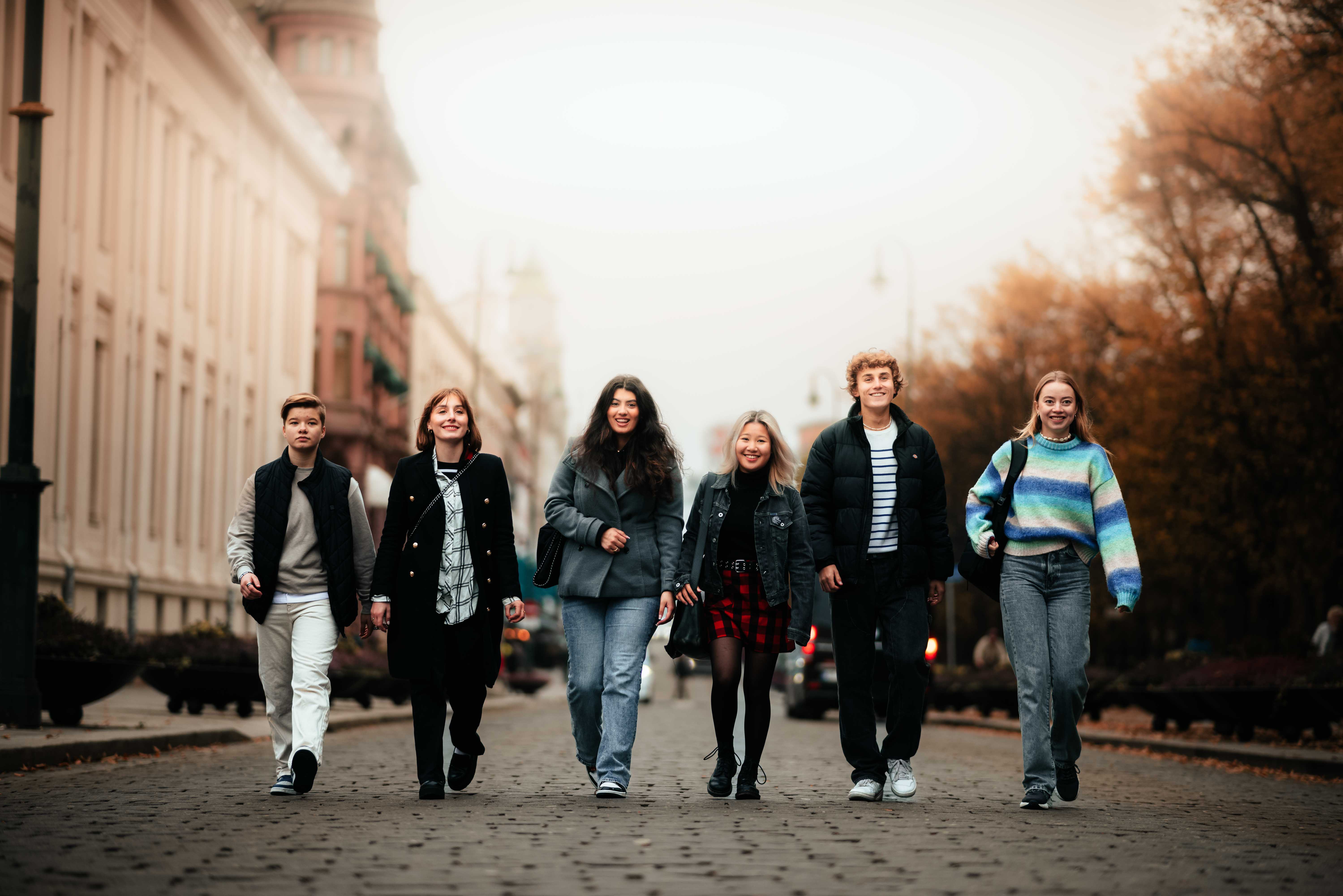 Seks studenter som går i en gate.