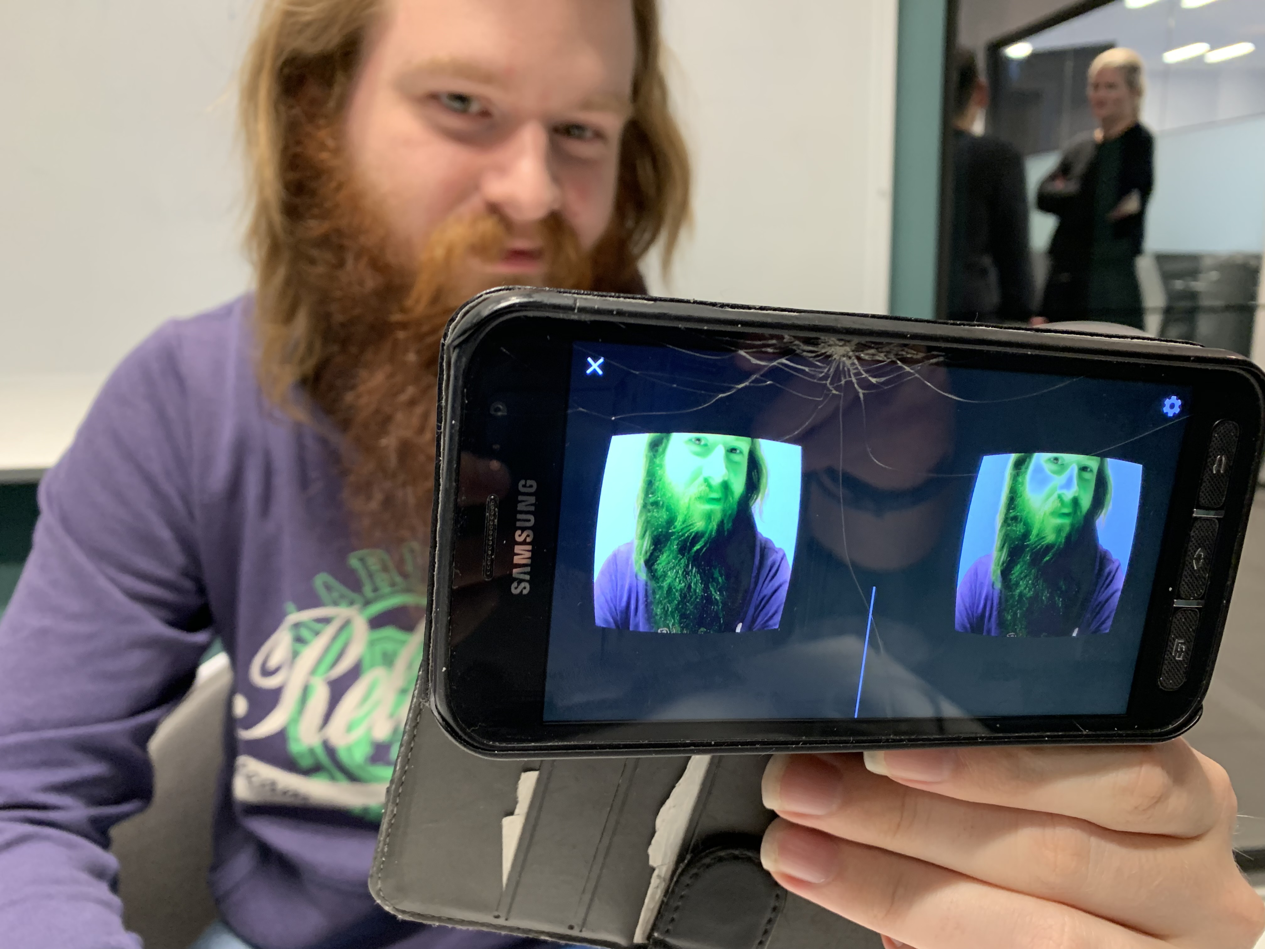 Mann med skjegg filmer seg selv med mobil.