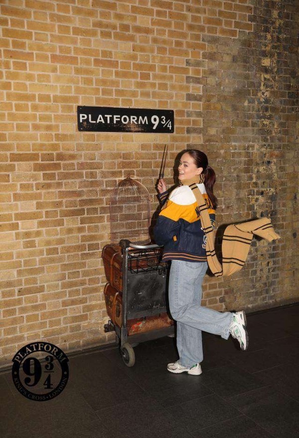 Jente foran murvegg med Harry Potter tilbehør