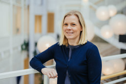 Dame med blondt hår i blå cardigan.