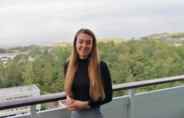 Foto av tidligere HR-student Kristine Brandal, her står hun på terrassen i sitt eget hjem i med utsikt over en skog.