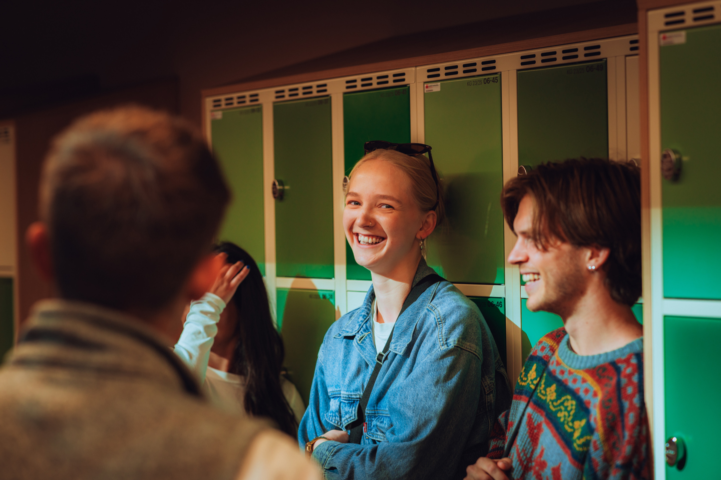 Bildelenke av fire studenter foran låsbare oppbevaringsskap på campus.