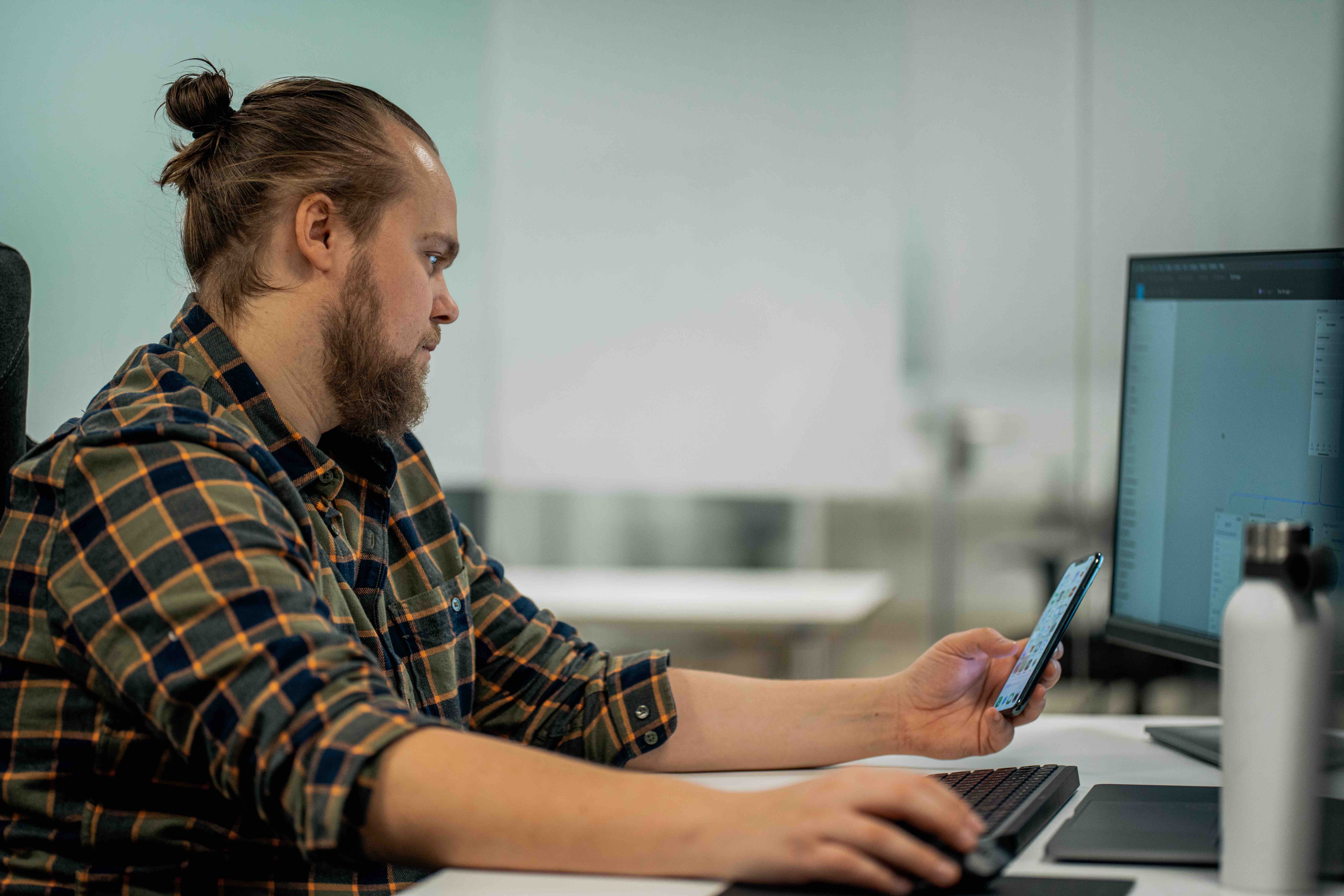Øyvind som sitter ved en kontorpult med telefonen og datamaskinen foran seg.