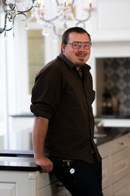 Robert Nybråten lener seg til kjøkkenbenk. 