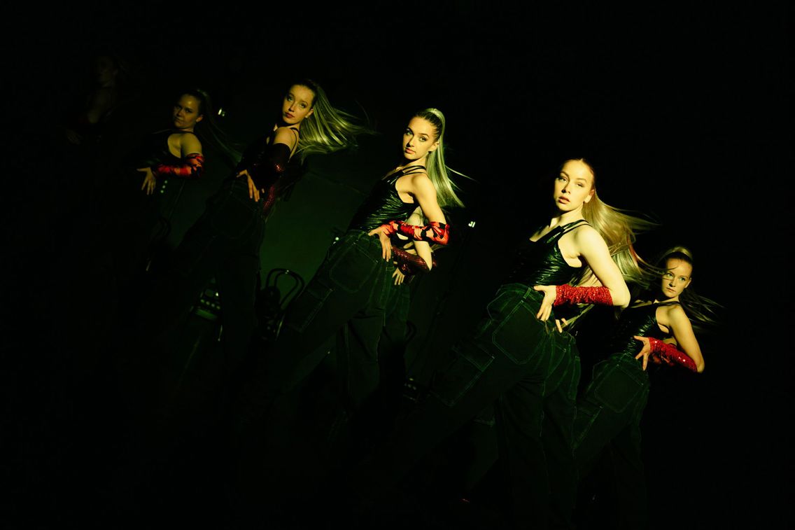 Fem dansere på en scene snur seg halvveis mot fotograf.