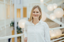 Dame i hvit skjorte lener seg på et rekkverk.