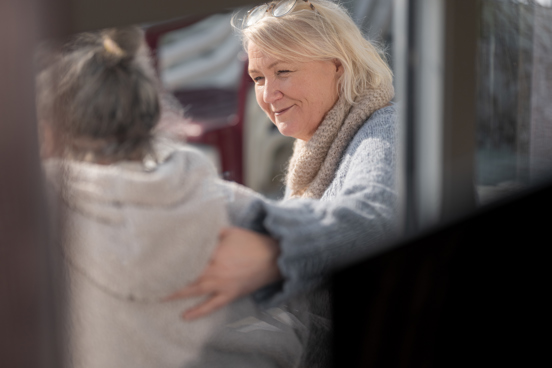 To personer i en samtale utendørs, der den personen legger hånden omsorgsfullt rundt den andre