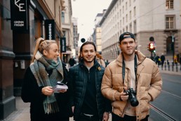 Tre studenter med kamera på en gate,