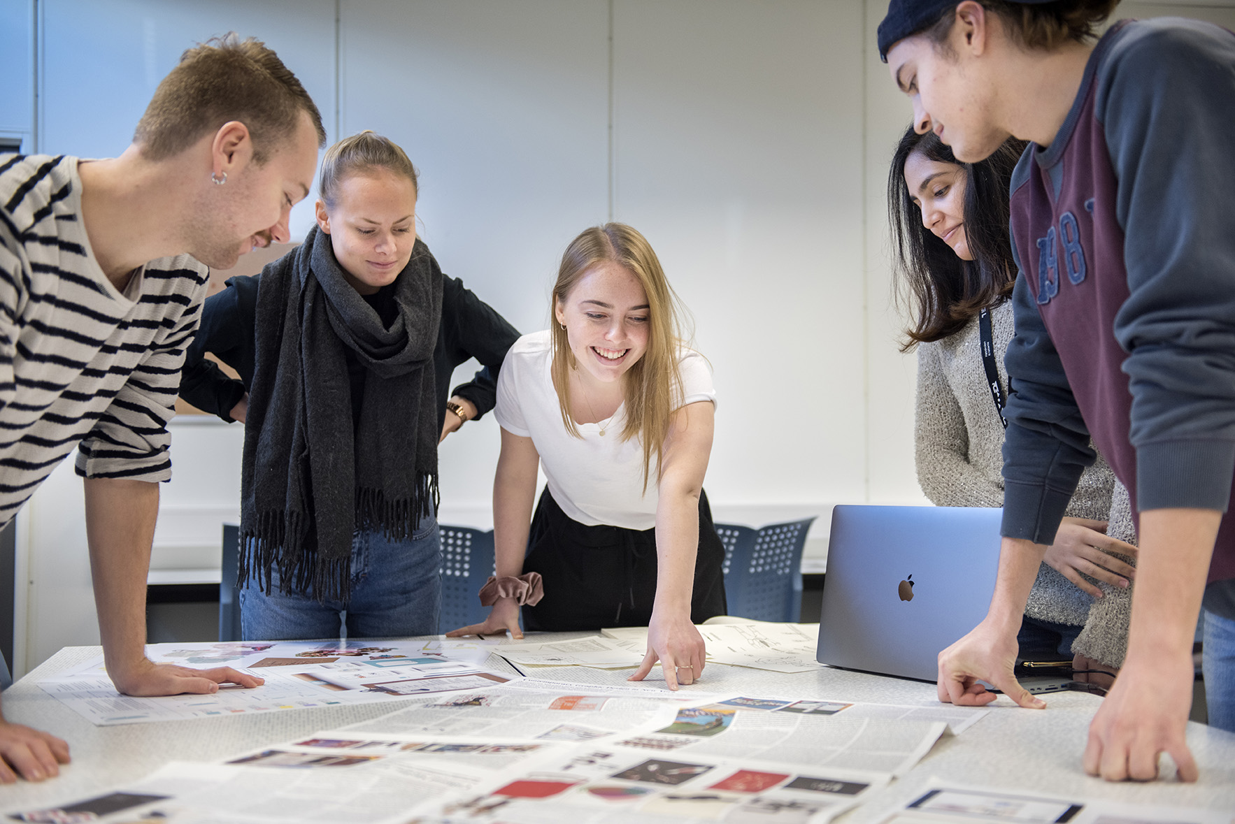 Studenter diskuterer skisser rundt et bord. Fagskolestudiet Grafisk Design ved Høyskolen Kristiania.
