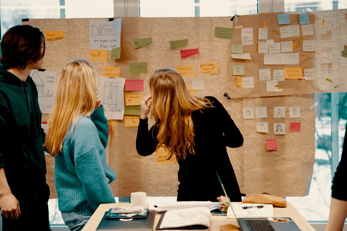Studenter foran tavle med post-it lapper.