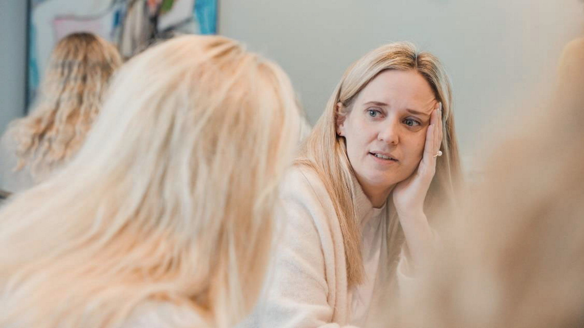 Ida sitter ved et bord og snakker til en person som har ryggen mot kamera.