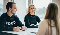 Tre studenter som sitter og diskuterer rundt et bord