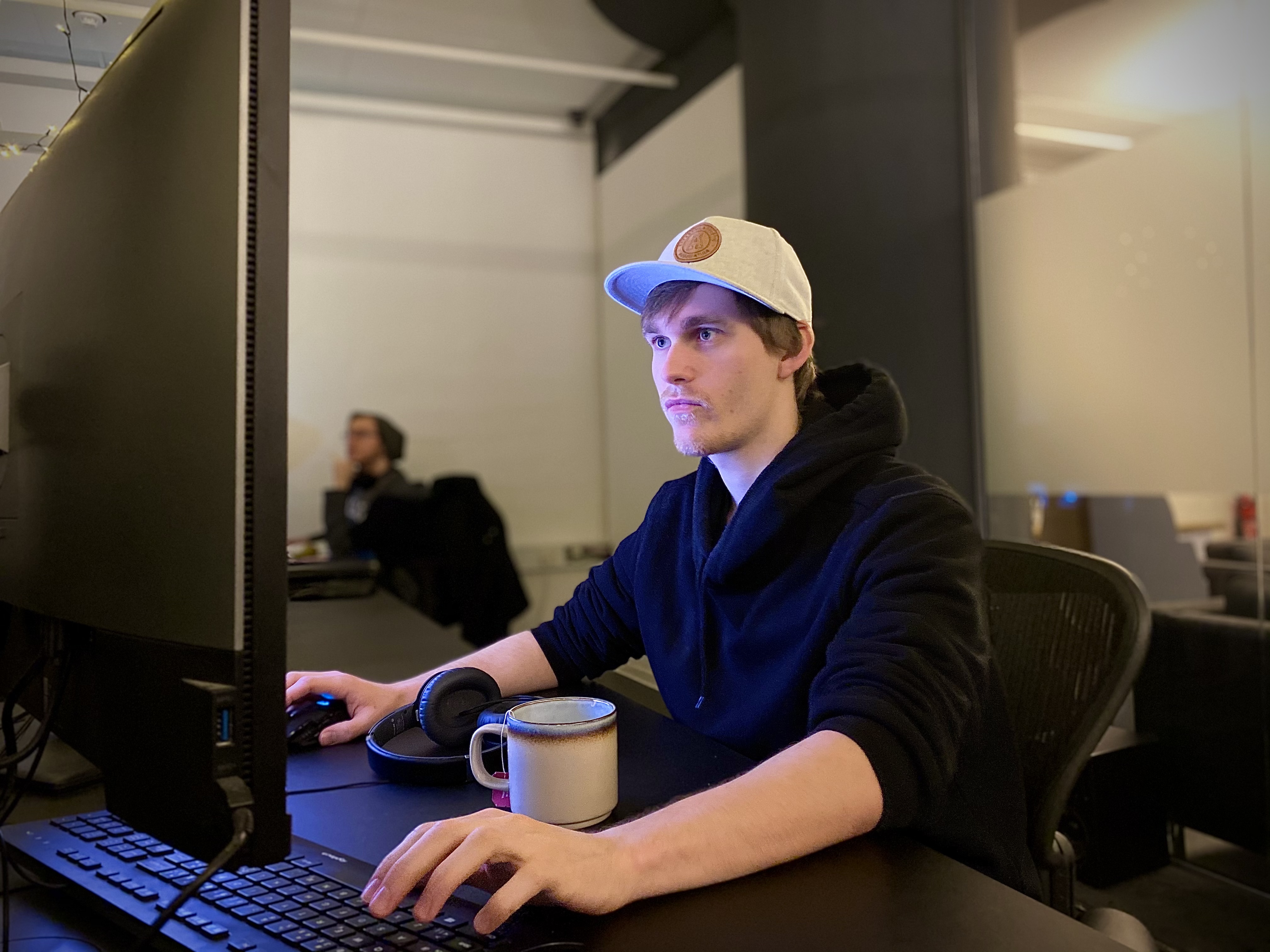 Foto av mann som sitter å ser på PC-skjerm 