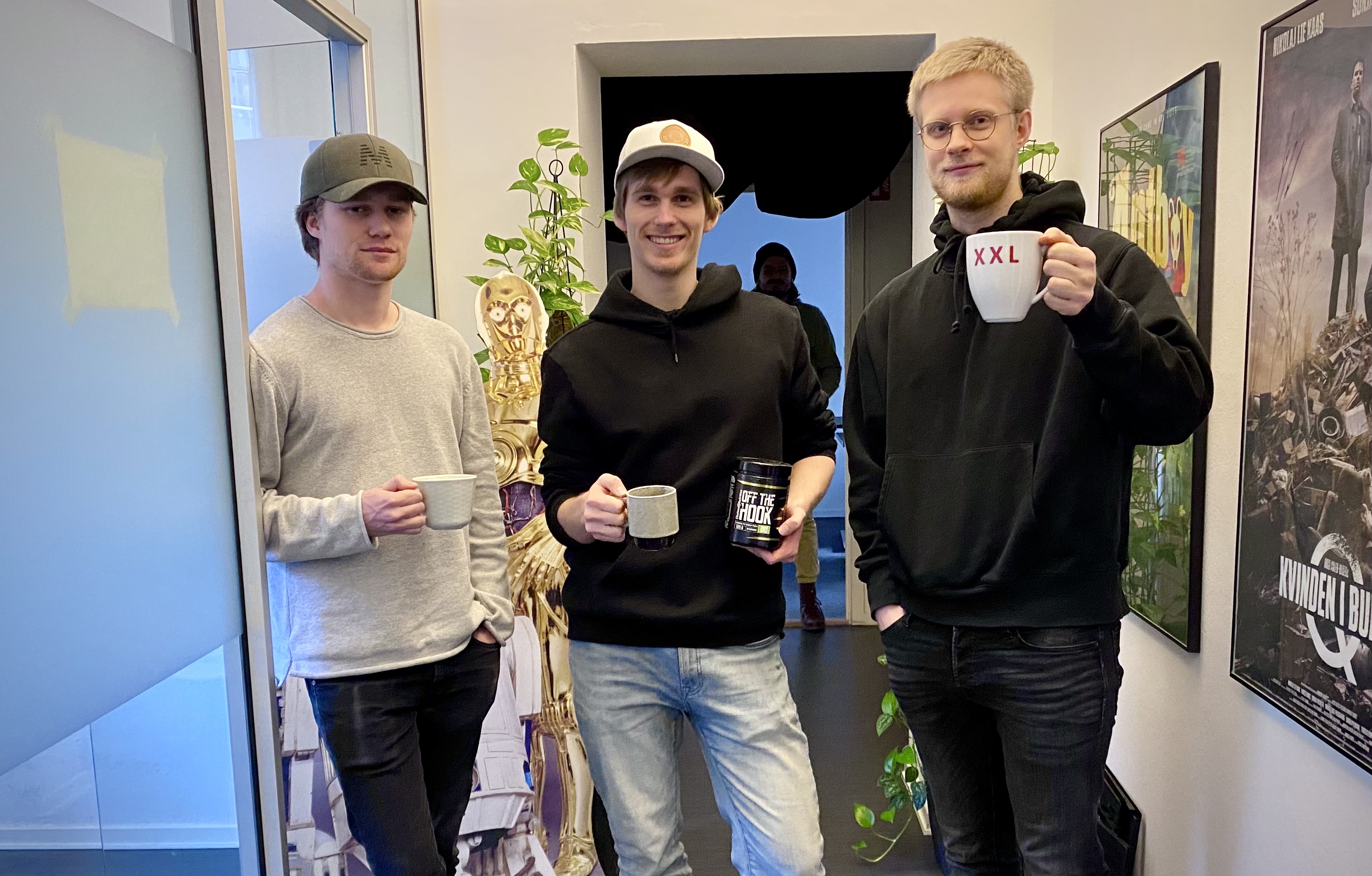 Tre menn som smiler og holder hver sin kaffekopp