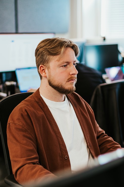 Bilde av Fredrik som sitter foran dataen på jobben sin TECHPROS.