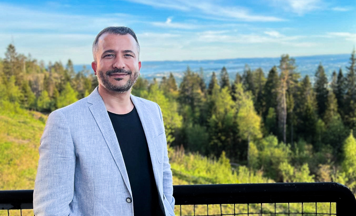 Ahmet Soylu står ved et rekkverk, med en skog i bakgrunnen.