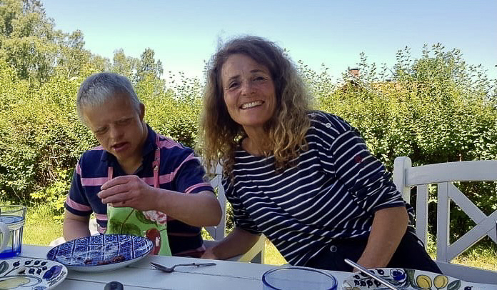 Voksent søskenpar sammen rundt et bord i hagen.