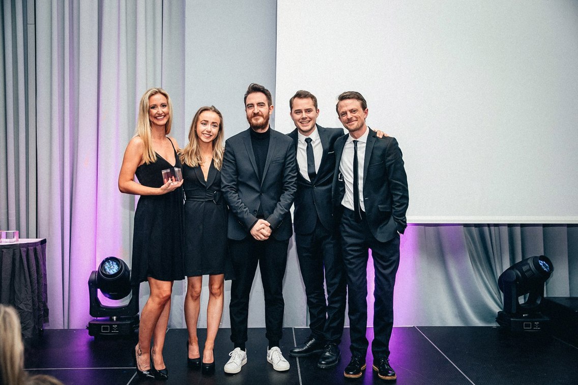Fem fra Reklamekollektivet står på scenen under Kuben 2019. De har nettopp mottatt en pris. 
