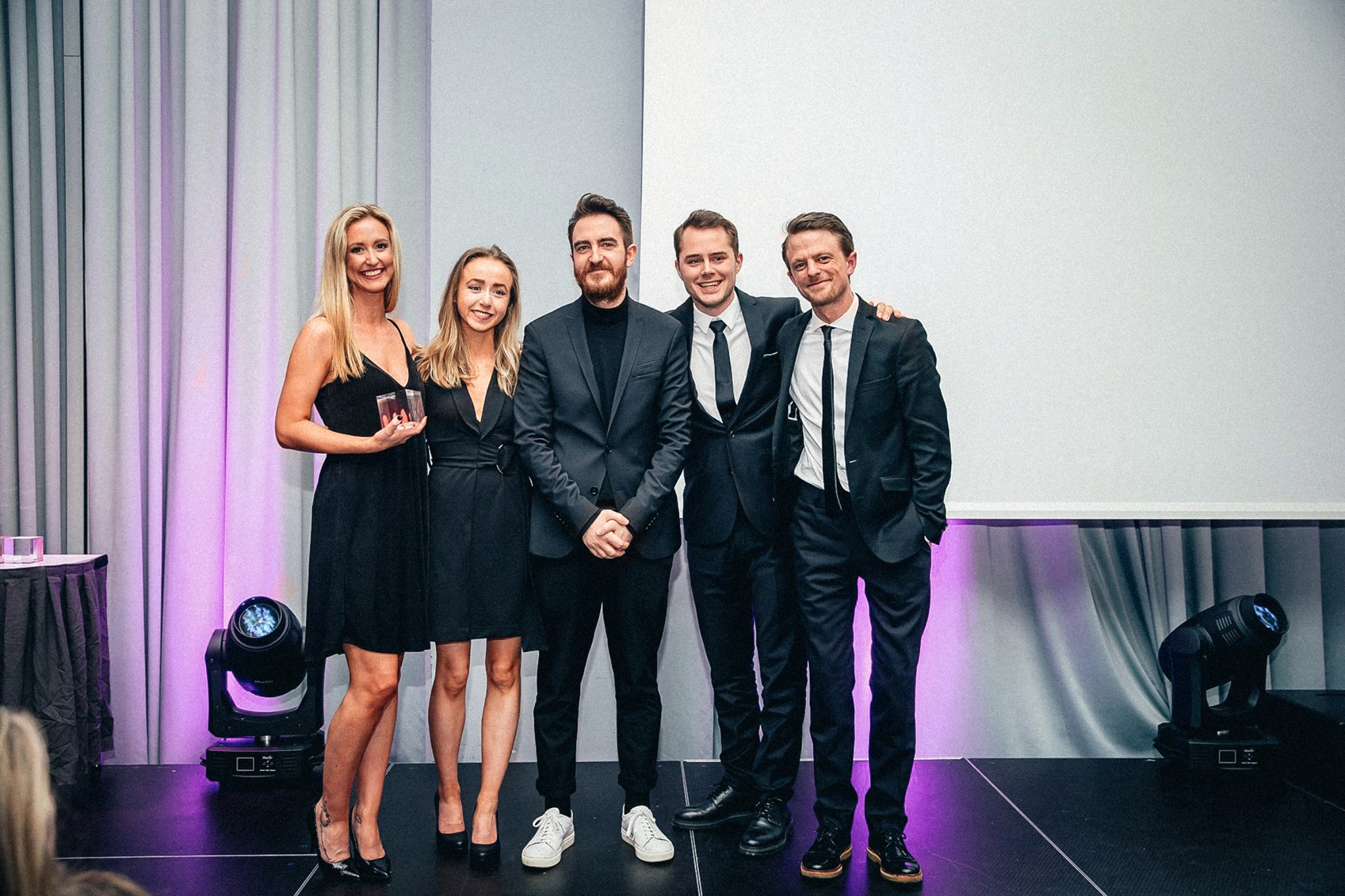 Fem fra Reklamekollektivet står på scenen under Kuben 2019. De har nettopp mottatt en pris. 