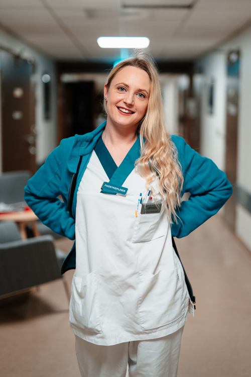 Cathrine stående i gangen på avdelingen hun jobber på.