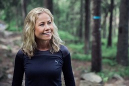 Smiling woman out in the nature with workout clothes on.