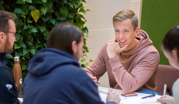 Ung mann i rosa hettegenser ser på medstudenter