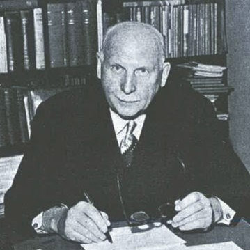 Foto av Ernst G. Mortensen som sitter ved sivebord.