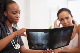 A female doctor is explaining to her female patient something on an Xray