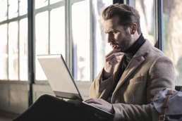 En mann som ser spørrende på pc-en sin som han har i fanget