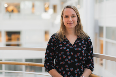Foto av blond kvinne i blomstret topp oppstilt for kamera.