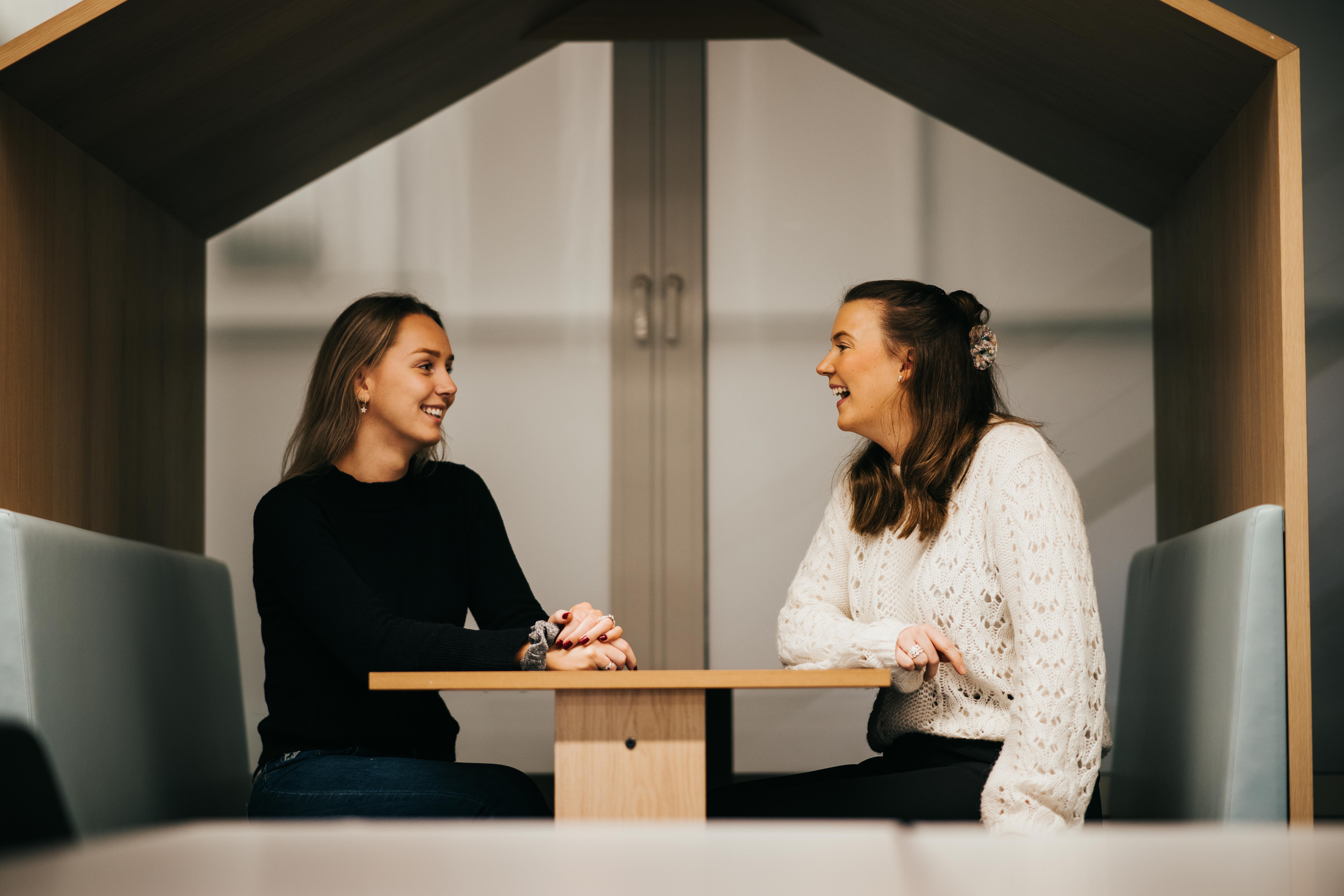 Kvinnelige studenter i sittegruppe på Høyskolen Kristiania. De ser på hverandre og ler.