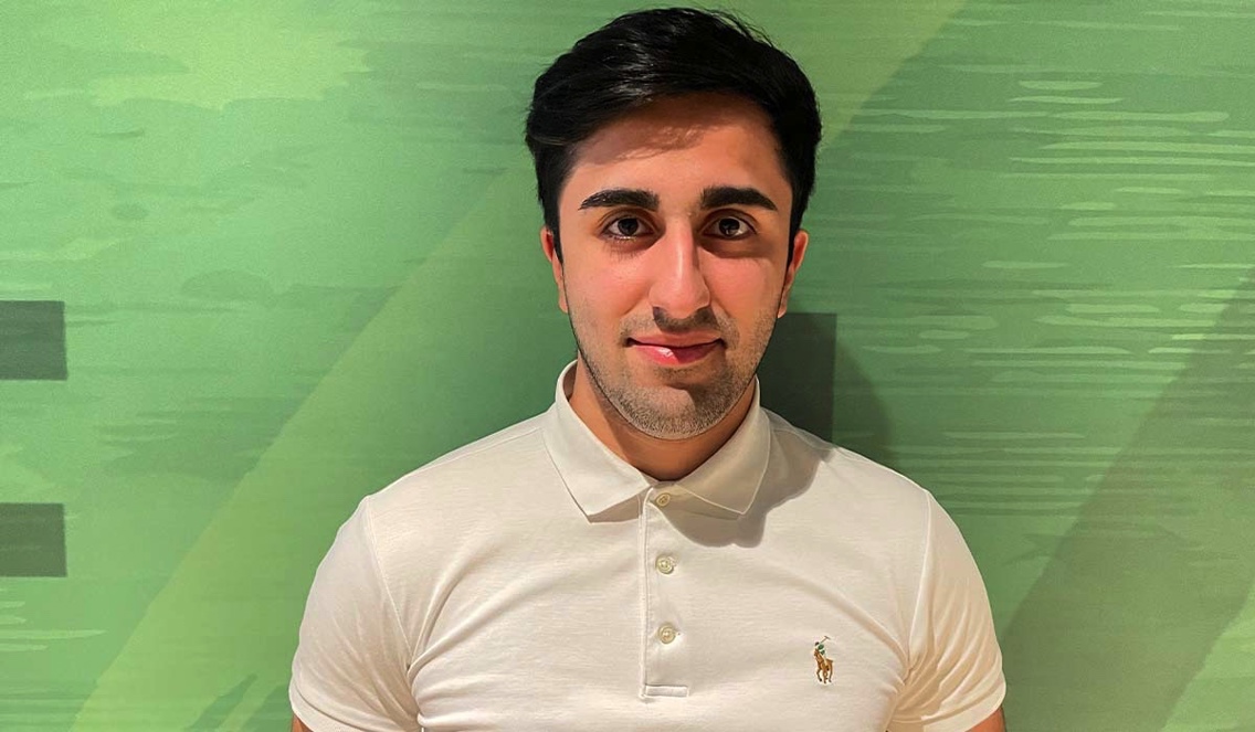Høyskolen Kristiania-student Nima Ranjbari  smiler til kamera mens han står foran en grønn vegg