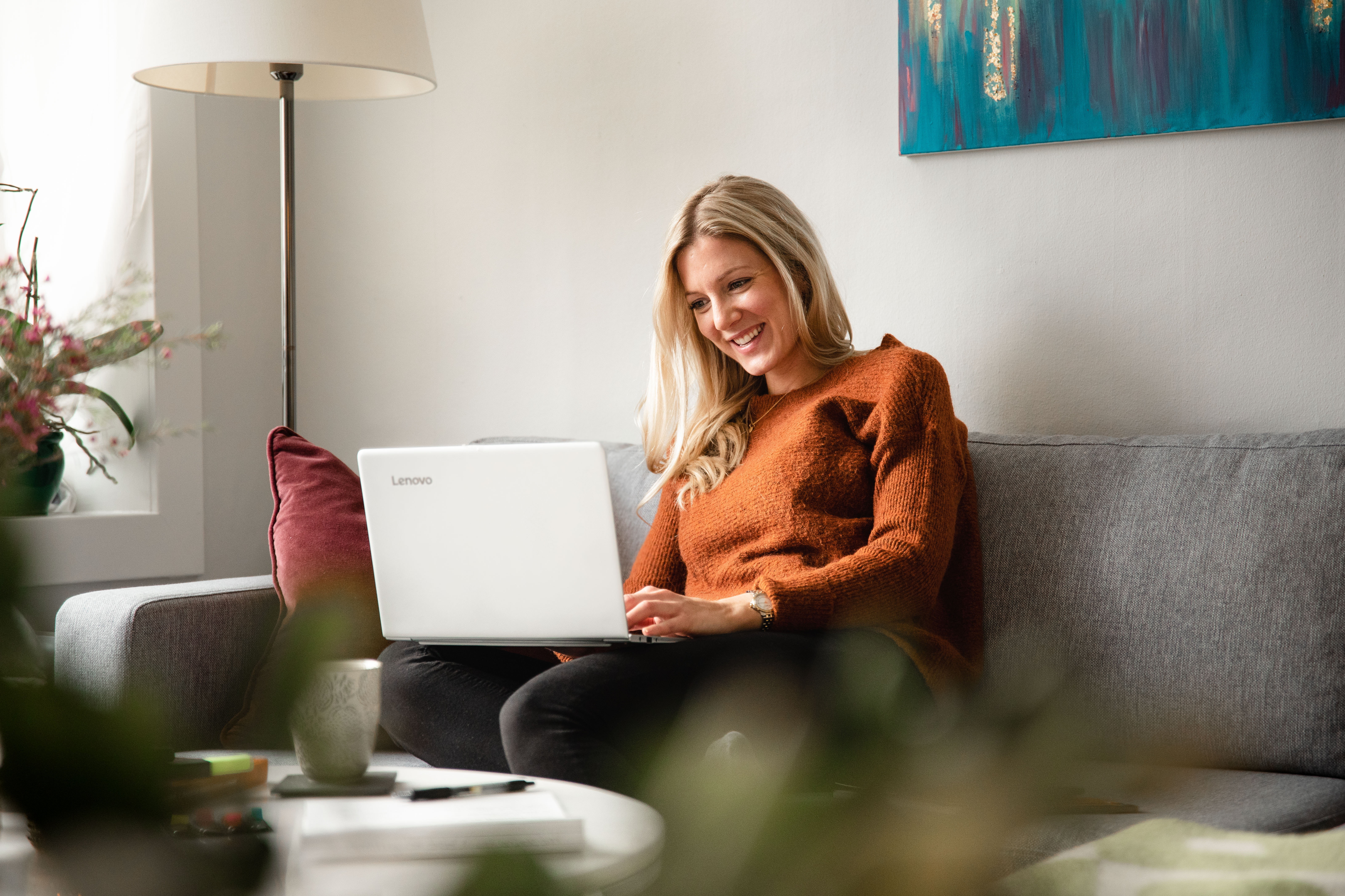 Kvinne som sitter i en sofa og jobber på PC